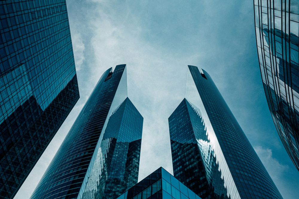 Glass skyscrapers against a blue sky. Photo: Charles Puaud / Unsplash