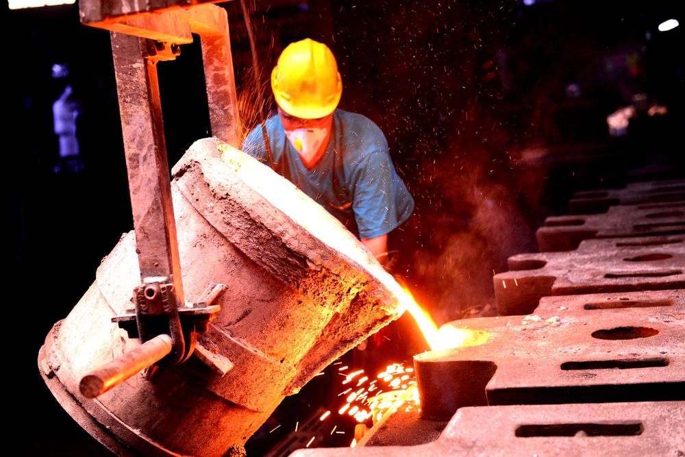 A foundry worker pouring molten metal into moulds. Photo: enes çimen / Pexels